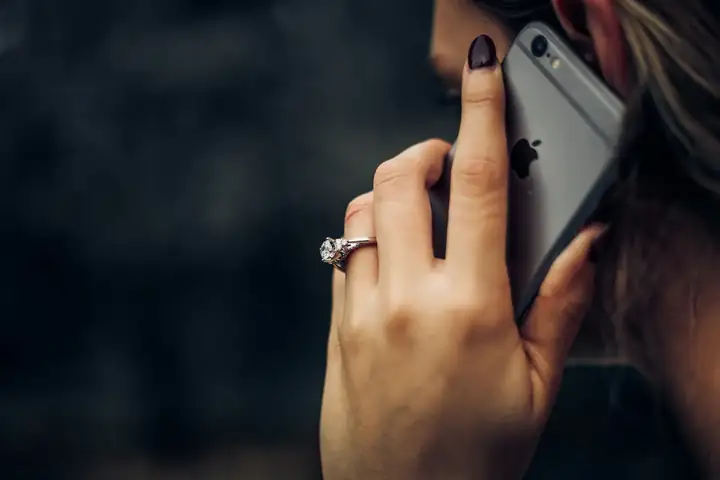 Woman in a white top talking on her phone while looking away